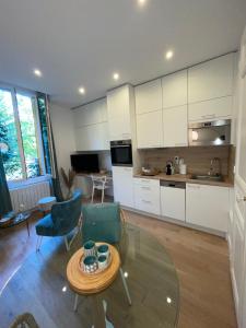 a kitchen with white cabinets and a table and chairs at Appartement François 1er in Vichy
