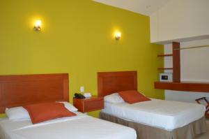 two beds in a room with yellow walls at Concierge Plaza La Villa in Colima +16 photos
