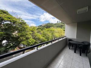 a balcony with a table and chairs and a view at Travessa 12 - Suítes centro de Serra Negra - SP in Serra Negra