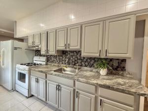 a kitchen with white cabinets and a sink and a refrigerator at Modern apartment close to NYC in North Bergen
