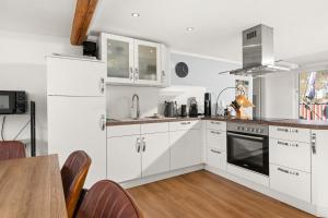 a white kitchen with white cabinets and a table at Tucan - Rooftop Terrace with View, BBQ, PS4+Stream in Marburg an der Lahn