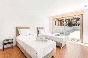two beds in a room with a large window at GuestReady - Charming beachside retreat in Mindelo