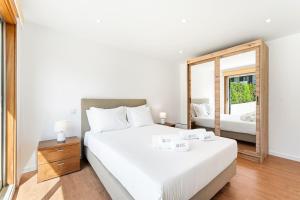 a bedroom with a large white bed and a mirror at GuestReady - Charming beachside retreat in Mindelo