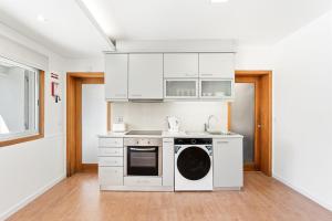 a kitchen with white cabinets and a dishwasher at GuestReady - Charming beachside retreat in Mindelo