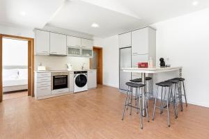 a kitchen with white cabinets and bar stools at GuestReady - Charming beachside retreat in Mindelo
