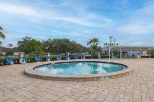 a swimming pool with blue chairs and a building at Pool Access + Course View: Golf Getaway in Sebring in Sebring