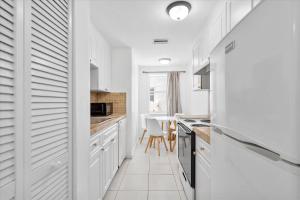 a white kitchen with white cabinets and a table at Coastal Sunset in Hollywood
