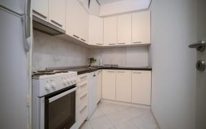 a white kitchen with white appliances and white cabinets at Olive View apartment in Rafailovici