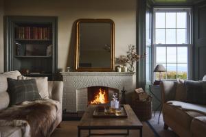 a living room with a fireplace and a mirror at Banchory Farm in Fife