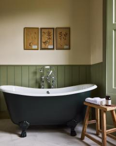 a bath tub in a green bathroom with three pictures at Banchory Farm in Fife +120 photos