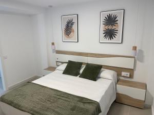a bedroom with a bed with white sheets and green pillows at Apartamentos San Antonio - GrupoAMI in Ontinyent