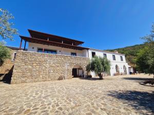 a large white building with a stone wall and trees at Convento da Provença in Portalegre