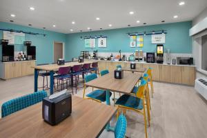 a restaurant with tables and chairs and a kitchen at Garner Hotel Lincoln North by IHG in Lincoln