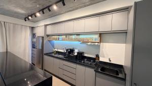 a kitchen with white cabinets and a black counter top at Royal ID Setor Oeste in Goiânia