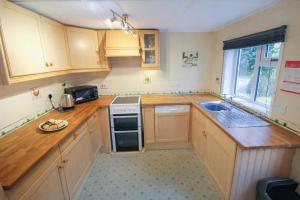 a small kitchen with wooden cabinets and a sink at Grasmere View, stunning views over Grasmere Lake, ideal romantic break in Grasmere