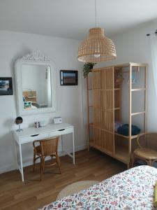 a bedroom with a desk and a mirror and a bed at Villa Joret in Fermanville