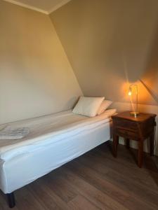 a bed in a room with a lamp on a table at SteneBo in Stenestad