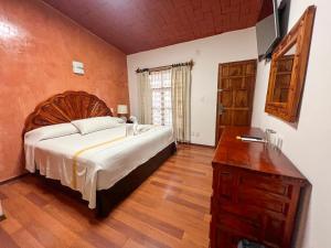 a bedroom with a large bed and a wooden dresser at Hotel Anua Oaxaca in Oaxaca City