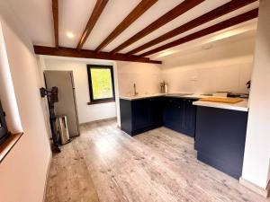 a kitchen with blue cabinets and a wooden floor at La Campagnarde, Maison de campagne proche Bapaume in Flers