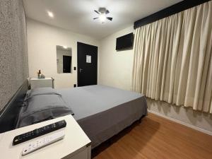 a bedroom with a bed and a remote control at Travessa 12 - Suítes centro de Serra Negra - SP in Serra Negra