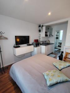 a white bedroom with a large bed and a kitchen at Charmant studio - Vanves in Vanves