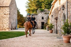 two people riding on horses down a street at Manoir La Ville Durand in Binic