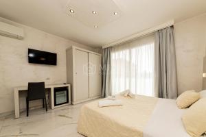 a bedroom with a white bed and a tv on the wall at Riviera Luxury Rooms in Porto Cesareo