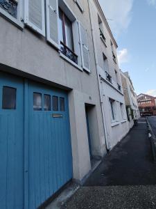 a building with a blue garage door on a street at Charmant studio - Vanves in Vanves +1 photo