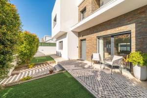 a patio with two chairs and a lawn at GuestReady - Aroeira Pool Villa in Setúbal