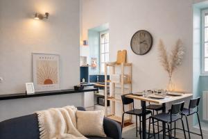 a living room with a table and a clock on the wall at Duplex - Place du Parlement de Bretagne - Hyper Centre de Rennes in Rennes