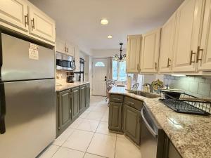 a kitchen with a stainless steel refrigerator and gray cabinets at Cozy Manhattan View Suite in West New York