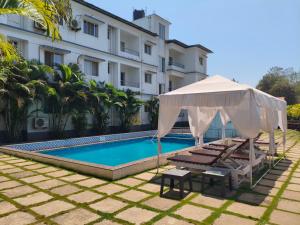 a hotel with a swimming pool with chairs and a white umbrella at Dacha by Great Host in Arambol