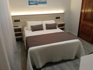 a bedroom with a large bed with two pillows at Pensión Plaza in Quintáns