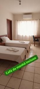 a hotel room with two beds and a sign on the floor at Fazio Hotel in Jales +1 photo