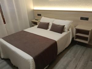 a bedroom with a large bed with two pillows at Pensión Plaza in Quintáns
