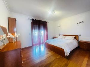 a bedroom with a bed and a wooden floor at Cantinho da Paz in Marinhas