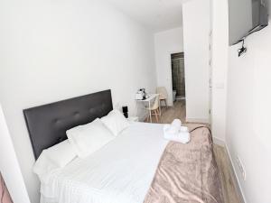 a white bedroom with a large bed with white sheets at Lofts IFEMA CH in Madrid