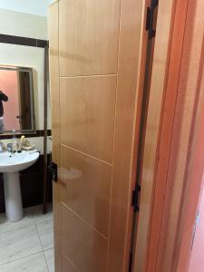 a bathroom with a wooden door next to a sink at harhoura Résidence Badia in Temara