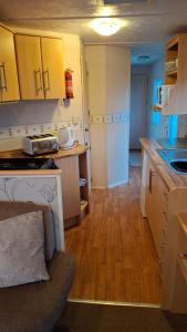 a kitchen with yellow cabinets and a wooden floor at Comforts caravan in Winthorpe +11 photos