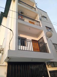 a tall white building with a balcony and a gate at RESIDENCE Tanta in Douala