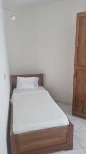 a bed with white sheets and a wooden frame in a room at RESIDENCE Tanta in Douala
