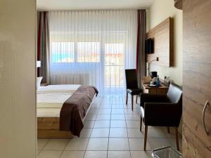 a hotel room with a bed and a desk and a window at Hotel Nahetal in Gensingen