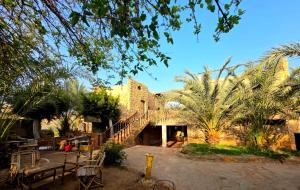 a building with a staircase and some chairs and trees at Old Oasis Hotel for Safari Trips in Az Zabū
