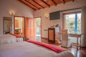 a bedroom with two beds and a desk and a television at Tocuyeros Boutique Hotel in Cusco