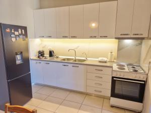 a kitchen with white cabinets and a sink and a refrigerator at Luce Apartment in Shkodër