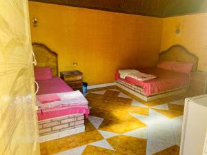 two beds in a room with yellow walls at Old Oasis Hotel for Safari Trips in Az Zabū