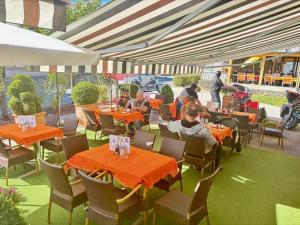 a group of people sitting at tables in an outdoor restaurant at Gästehaus Trink B&B in Drobollach am Faaker See