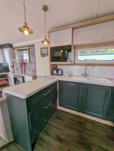 a kitchen with green cabinets and a sink at Swift Bordaux 68 in Ardentinny +2 photos