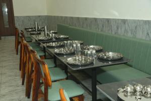 a row of tables and chairs with plates and glasses at Hotel Akash Palace in Shāhpur