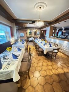 a restaurant with white tables and chairs and a chandelier at Gästehaus Trink B&B in Drobollach am Faaker See
